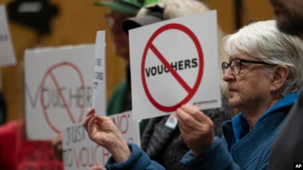 FILE - Mirabelle Stoedter holds a sign against school vouchers during a news conference, Nov. 28, 2023, in Nashville, Tenn., wher<em></em>e Tennessee Gov. Bill Lee presented the Education Freedom Scholarship Act of 2024.