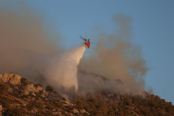 A firefighting helicopter drops water at a resurgence near Nea Makri